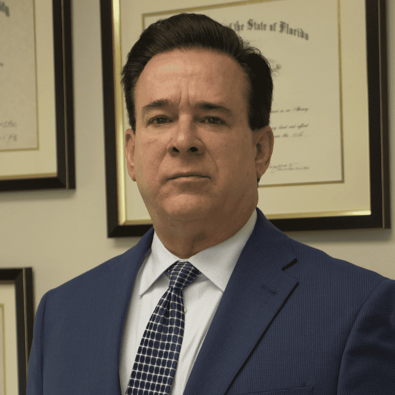 Attorney in formal suit with law degrees in the background, representing legal services at Flores Law Miami.